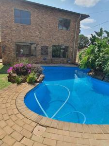 a blue swimming pool in front of a house at Funky Dot Sleeping Spot in Kempton Park
