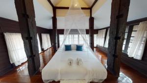 a bedroom with a white bed in a room with windows at DONPIN8-Timeless House Chiang Mai in Chiang Mai