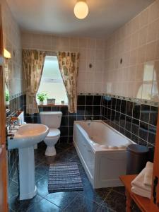 a bathroom with a tub and a toilet and a sink at Rockgardencottage in Lettermacaward