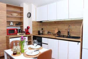 a kitchen with white cabinets and a table with chairs at Shik & Chic in the Heart of Burgas # 5min from beach # New in Burgas