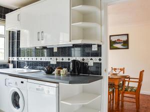 kuchnia z białymi szafkami, pralką i suszarką w obiekcie Brookside w mieście Coychurch