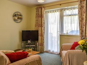 een woonkamer met een bank, een tv en een raam bij Farriers in Bransgore