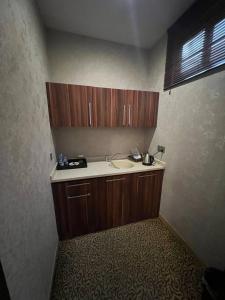 a kitchen with a sink and wooden cabinets in a room at Jouhayna Hotel&Suite in Erbil