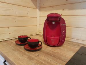 a red coffee maker with two cups on a table at Chata Rafusa pod Śnieżnikiem in Stronie Śląskie