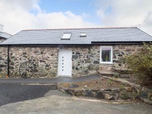 a stone house with a white door and a window at Bryn Eglwys in Llanegryn