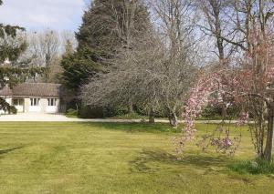 un patio con una casa y un árbol con flores rosas en Garden Cottage, Five Pines en Acton Turville