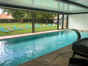 a swimming pool with blue lounge chairs in a yard at Logement @ 10 personnes avec piscine intérieure 31 degrés zoo de la FLECHE 24 h du Mans in La Flèche