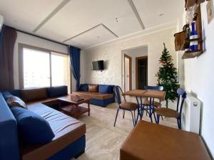 a living room with a couch and a table with a christmas tree at L'APPARTEMENT PARADISIAQUE A HAMMAMET ET NABEUL in Nabeul