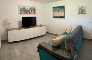 sala de estar con sofá y TV de pantalla plana en Sardegna Beach Ginepro, en Olbia