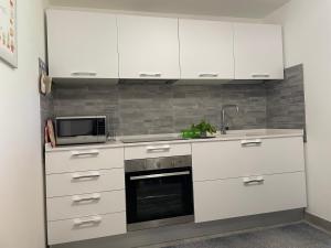 a kitchen with white cabinets and a microwave at Sardegna Beach Ginepro in Olbia