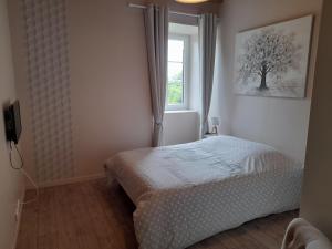 Schlafzimmer mit einem Bett und einem Fenster in der Unterkunft Gîte de charme Les Prunes de la Souleuvre in Le Reculey