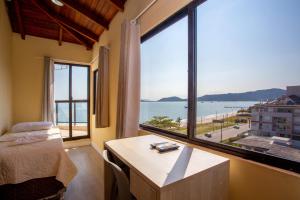 a bedroom with a large window with a view of the ocean at Hotel Vila Mar in Florianópolis