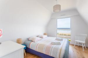 a white bedroom with a bed and a window at La Grande Plage in Saint-Cast-le-Guildo