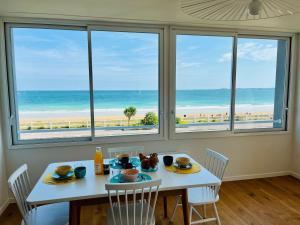 a dining room with a table and views of the beach at La Grande Plage in Saint-Cast-le-Guildo