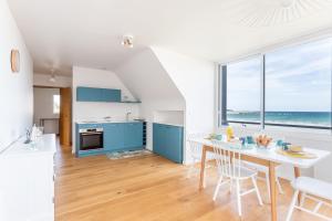 Una cocina con gabinetes azules y una mesa con sillas. en La Grande Plage, en Saint-Cast-le-Guildo 9 fotos más