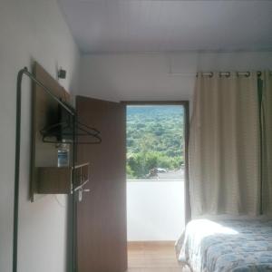 a bedroom with a bed and a large window at Recanto Bela Vista serra in Tiradentes