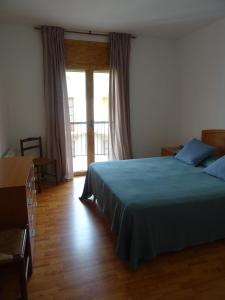 a bedroom with a blue bed and a balcony at Pis Acollidor amb LLar de Foc, al Centre Camprodon in Camprodon
