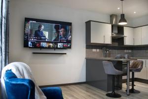 a kitchen with a tv hanging on a wall at The Countryman Den - 65 Inch TV - Super Wifi in Gillingham