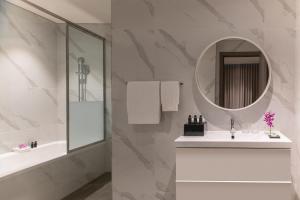 a white bathroom with a sink and a mirror at Steigenberger Residence Doha in Doha