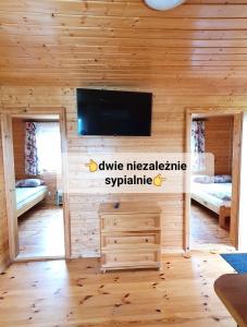 ポランチクにある,,KICZARA" Domki na Punkcie Widokowym POLAŃCZYK z widokiem na Jezioro Solińskie i góry, domki z klimatyzacją 601-806-454のテレビ付きの木製の壁の客室