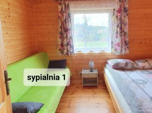 Un dormitorio con una cama verde y una ventana en ,,KICZARA" Domki na Punkcie Widokowym POLAŃCZYK z widokiem na Jezioro Solińskie i góry, domki z klimatyzacją 601-806-454, en Polańczyk