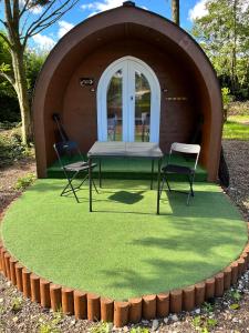 een tent met twee stoelen en een tafel in het gras bij Blackbrook lodge Camping pods in Belper