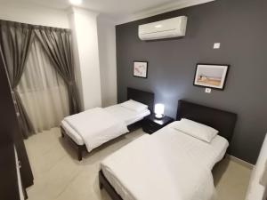 a bedroom with two beds and a air conditioner at Al Muftah Homes in Doha