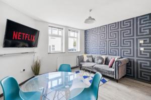 a living room with a glass table and blue chairs at The Countryman Corner - Smart TVs - Fast Wifi in Gillingham