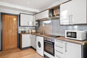 a kitchen with white cabinets and a microwave at The Countryman Corner - Smart TVs - Fast Wifi in Gillingham