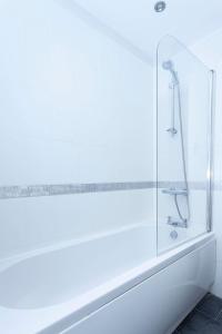 a white bathroom with a shower with a glass wall at Magnolia cove in Whitstable