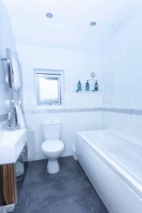 a white bathroom with a toilet and a bath tub at Magnolia cove in Whitstable