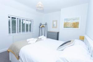 a white bedroom with two beds and a window at Magnolia cove in Whitstable