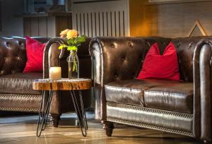 ヒンターシュトダーにあるLandhotel Gressenbauerの革張りのソファーと花瓶のテーブル