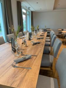 a long wooden table with chairs and glasses on it at Hotel Knotenpunkt in Meppen