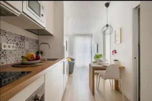 a kitchen with white cabinets and a table with a bowl of fruit at Apartment close to the beach in Sant Adria de Besos