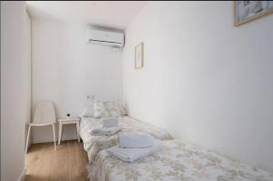 two twin beds in a white room with a table at Apartment close to the beach in Sant Adria de Besos