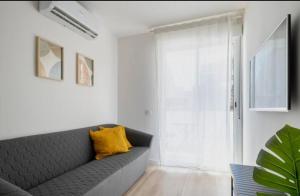 a living room with a gray couch and a yellow pillow at Apartment close to the beach in Sant Adria de Besos