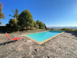 a red chair sitting next to a swimming pool at Les chambres de Testory in Montesquieu-Volvestre