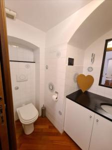 La salle de bains blanche est pourvue de toilettes et d'un lavabo. dans l'établissement LE MURA, à Gênes