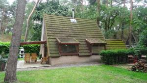 una pequeña casa con un techo verde en un patio en Chalet met wellness, en Lanaken