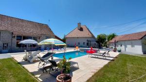 un patio trasero con piscina con sillas y sombrilla en Domaine Ravy-Orchidée, en Saint-Symphorien-sur-Saône
