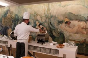 a chef preparing food in front of a painting at Hotel Royal Continental in Naples