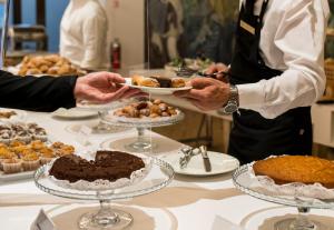 a person holding a plate of food on a table at Hotel Royal Continental in Naples