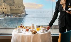 a man standing next to a table with food on it at Hotel Royal Continental in Naples