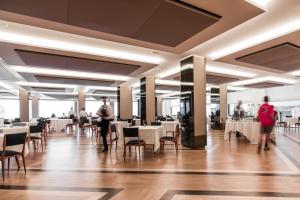 a dining room with white tables and chairs and people at Hotel Royal Continental in Naples