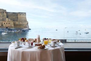 a table with food on it with a view of a castle at Hotel Royal Continental in Naples