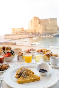 a table with a plate of breakfast foods and drinks at Hotel Royal Continental in Naples