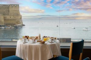 a table with food and a view of the ocean at Hotel Royal Continental in Naples
