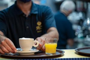 a man sitting at a table with a cup of coffee and orange juice at Hotel Royal Continental in Naples