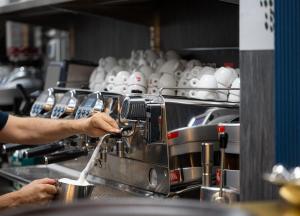 a man is making a coffee in a kitchen at Hotel Royal Continental in Naples